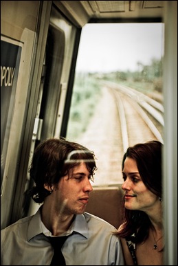 couple sitting in back of metro car with tracks in background
