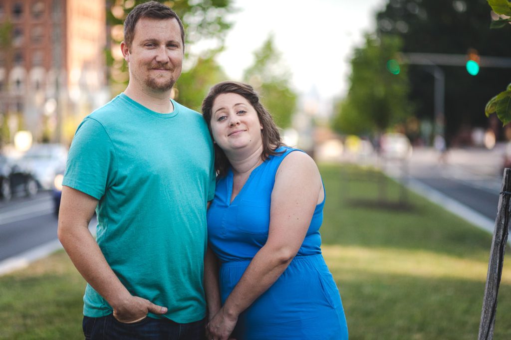 A man and woman pose for a picture in front of a tree.