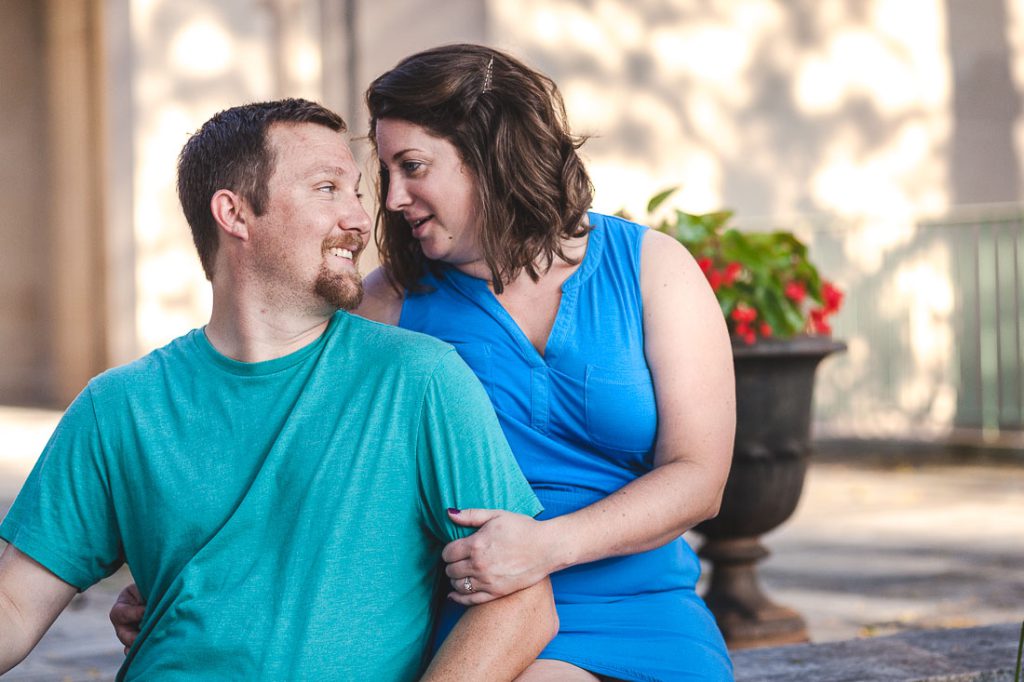 A man and woman are sitting on a bench in front of a building.
