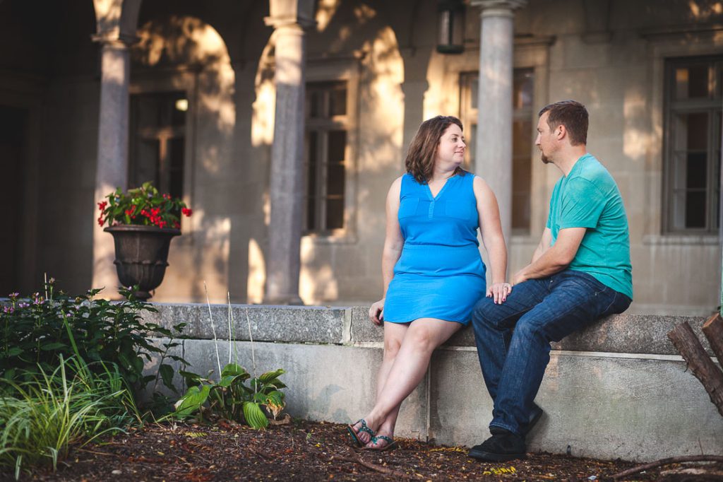 An couple sitting on a ledge in front of a building.