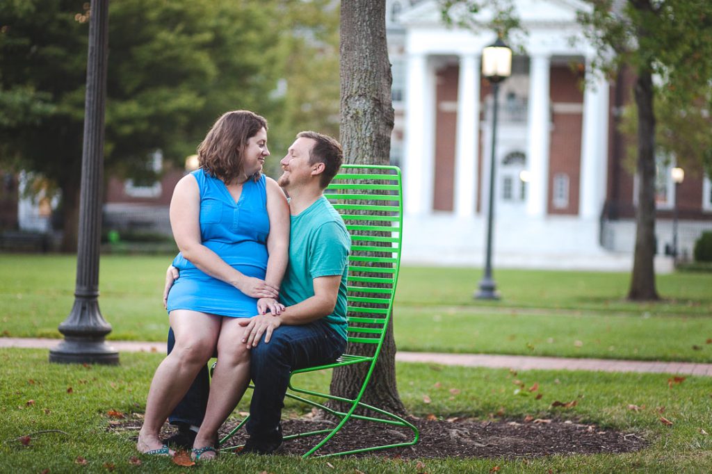 A couple sits on a bench in front of a tree.