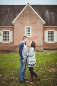A portrait of an engaged couple standing in front of a brick house in Downtown Annapolis.