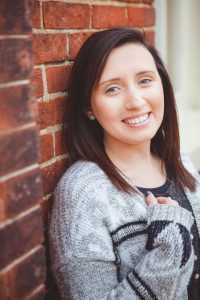 A woman wearing a sweater, leaning against a brick wall in downtown Annapolis.