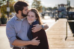 A couple embracing in a heartfelt engagement photo taken on a dock in downtown Annapolis.