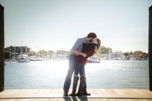 An engagement photo of a couple kissing on a dock in downtown Annapolis.