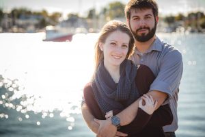 An engagement photo of a couple embracing in front of the water in Downtown Annapolis, creating a beautiful portrait.