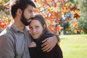 A couple hugging in front of a tree during their engagement photo shoot in downtown Annapolis.