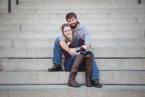 A couple sitting on the steps of a building in downtown Annapolis, capturing their engagement photo.