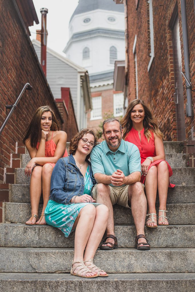 A family sits on steps in front of a building.