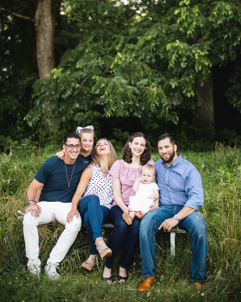 A family sits on a bench in a field.