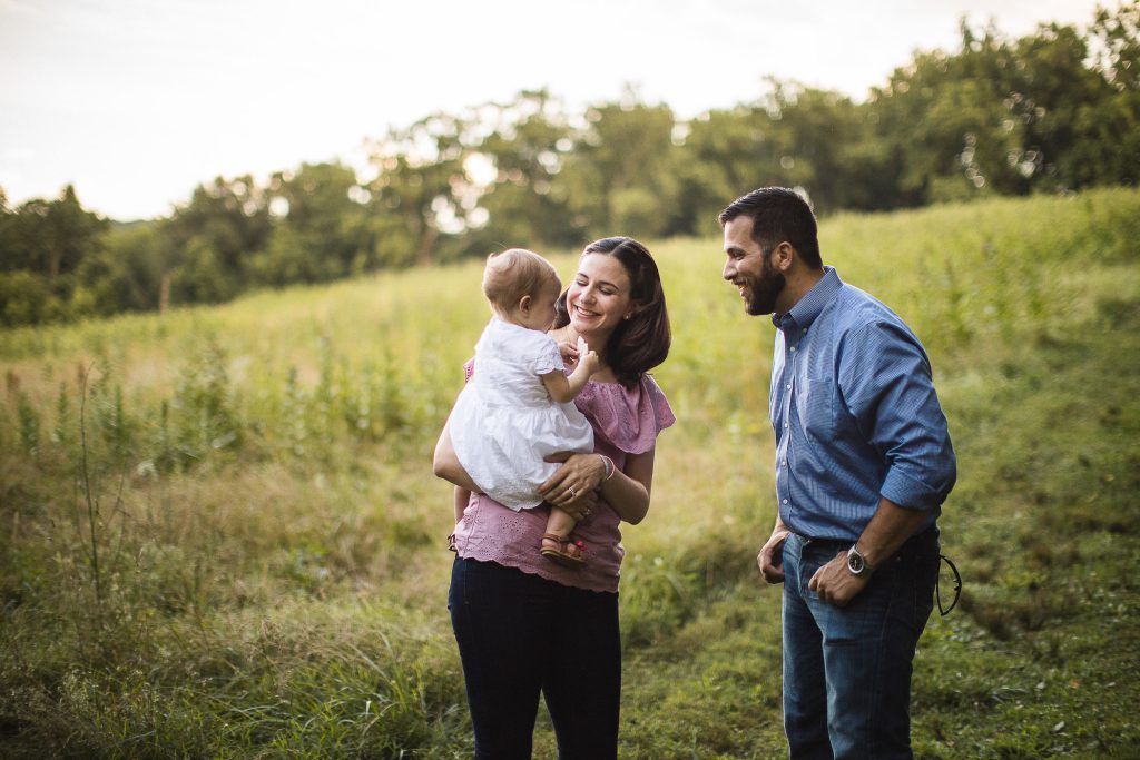 A man and woman holding a baby in a field.