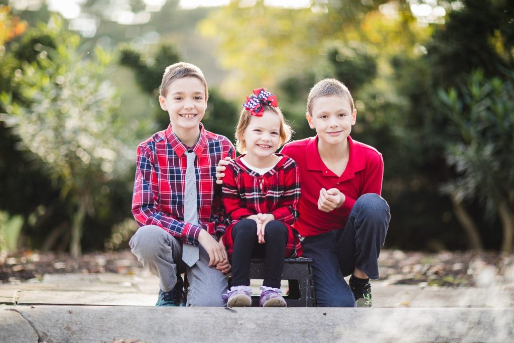 Three children posing for a family photo.