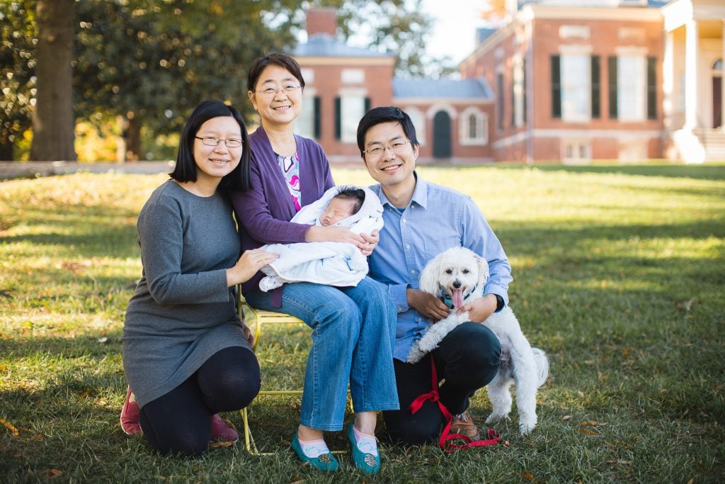 A family posing for a photo in front of a large house.
