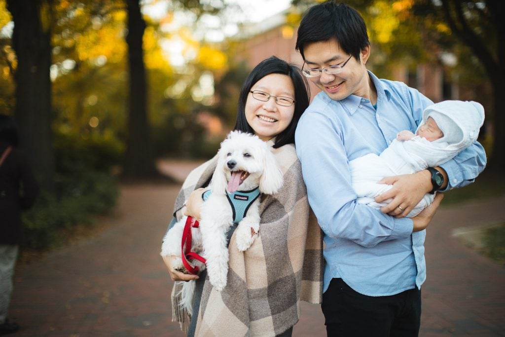 A man and woman holding a dog in a park.