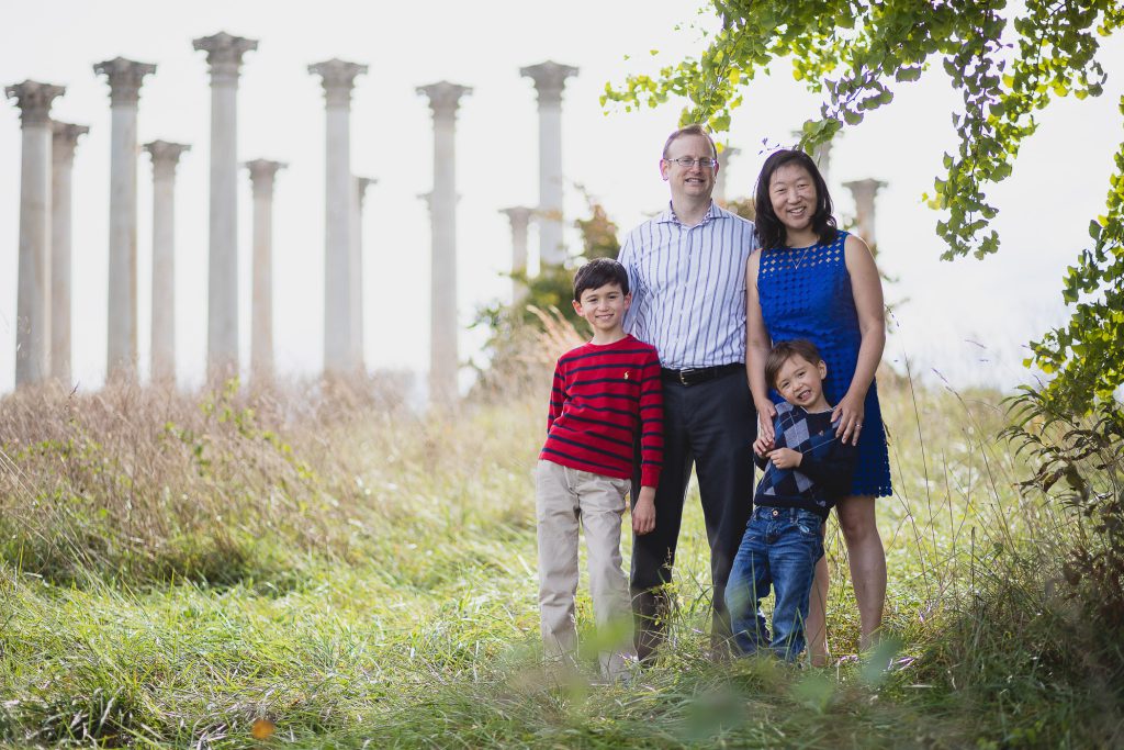 A family is posing in front of columns in a field.