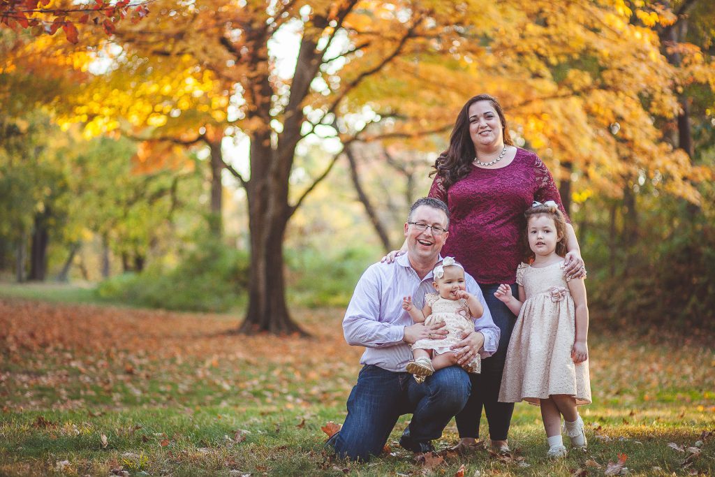 A family is posing for a family photo in the fall.