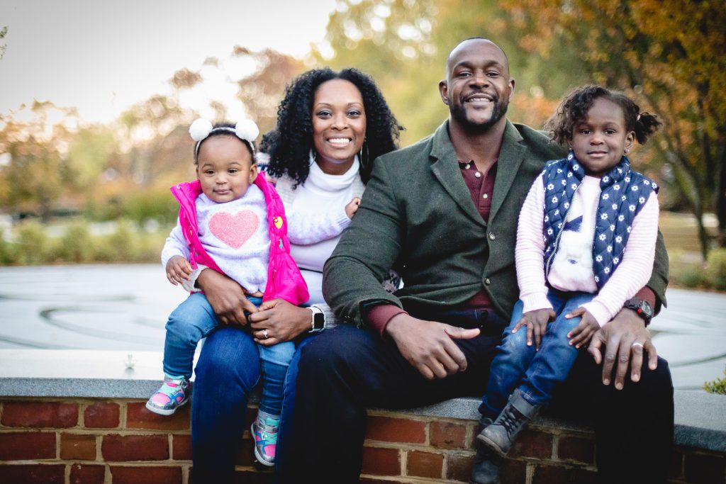A family sitting on a brick wall in a park.