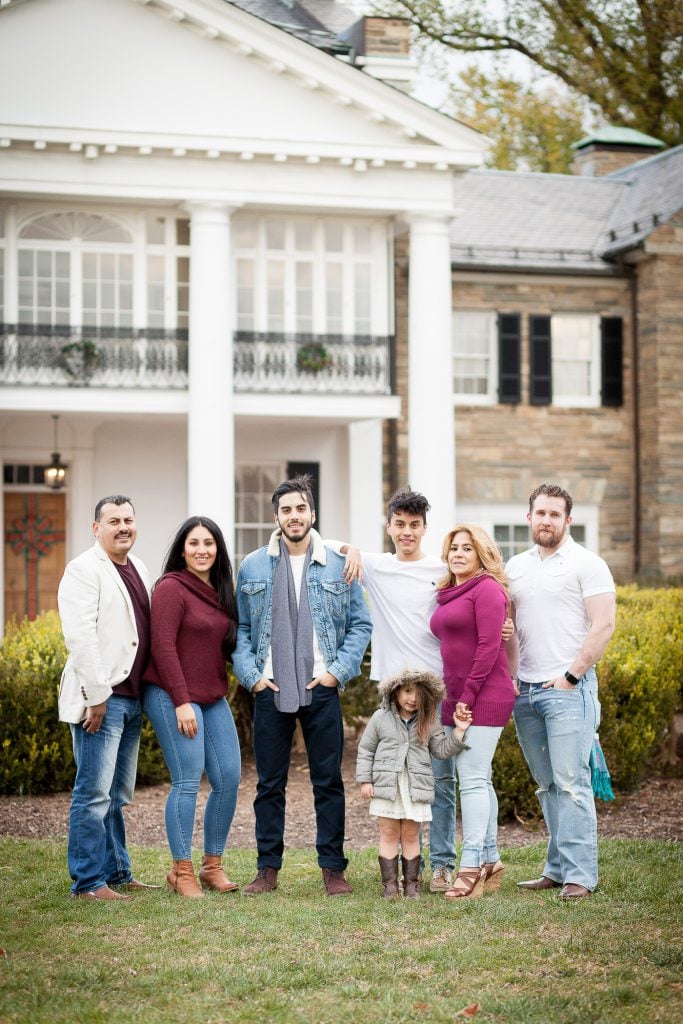 A family posing in front of a large mansion.