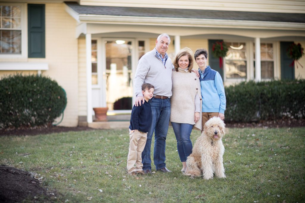 A family posing in front of a house with a dog.