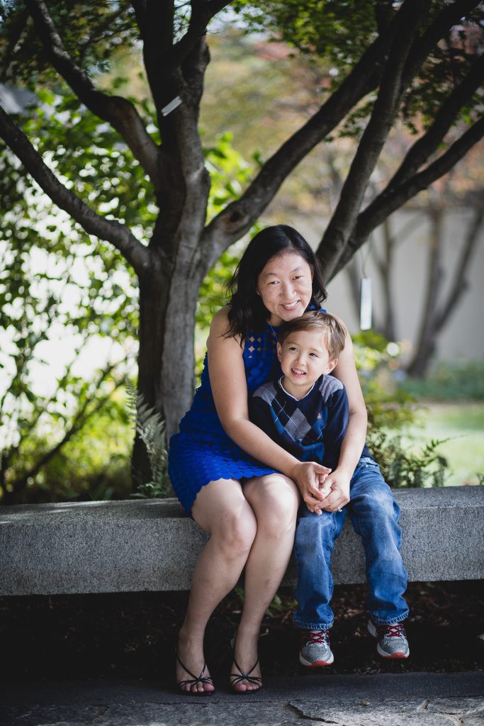 A family sitting on a bench under a tree.