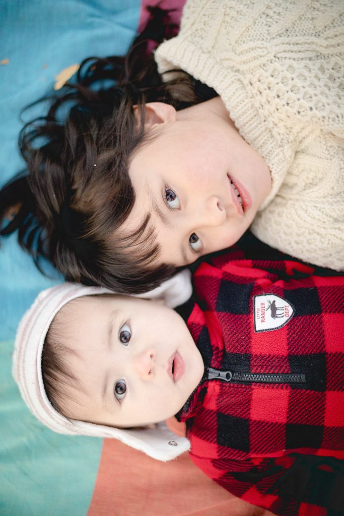 Family portrait featuring two small children laying on a blanket.