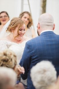A bride and groom smiling at each other during their wedding ceremony captured by a talented Maryland wedding photographer.