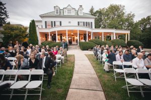 A wedding ceremony captured by a Maryland wedding photographer in front of a large house.