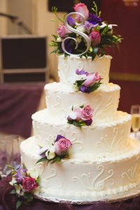 A three tiered white wedding cake covered in flowers.