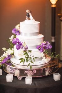 A white wedding cake with purple flowers on top captured by a Maryland wedding photographer.