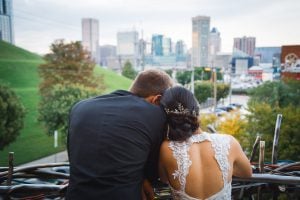 A bride and groom hugging on a railing overlooking the city in Annapolis.