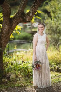 A bride in a wedding dress poses for a Maryland wedding photographer in front of a tree.