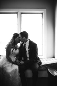 An Annapolis bride and groom kissing in front of a window.