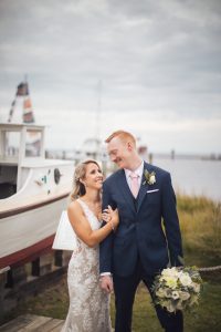A bride and groom standing in front of a boat captured by a Maryland wedding photographer.