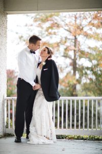 A bride and groom embracing on a porch captured by a Bowie Wedding Photographer.