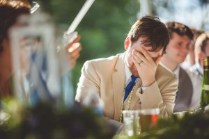A Maryland Wedding Photographer capturing a man in a suit covering his face at a wedding.
