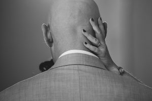 A bald man touching his head.