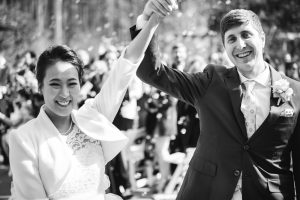 A black and white photo of a wedding ceremony with the bride and groom throwing confetti.