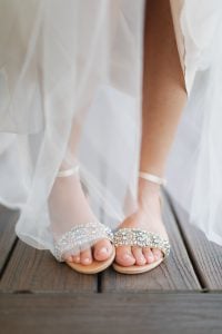 The wedding shoes on a wooden deck showcase beautiful wedding details.