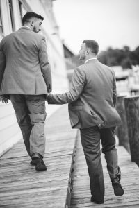 Two men in suits walking down a dock for a wedding portrait.