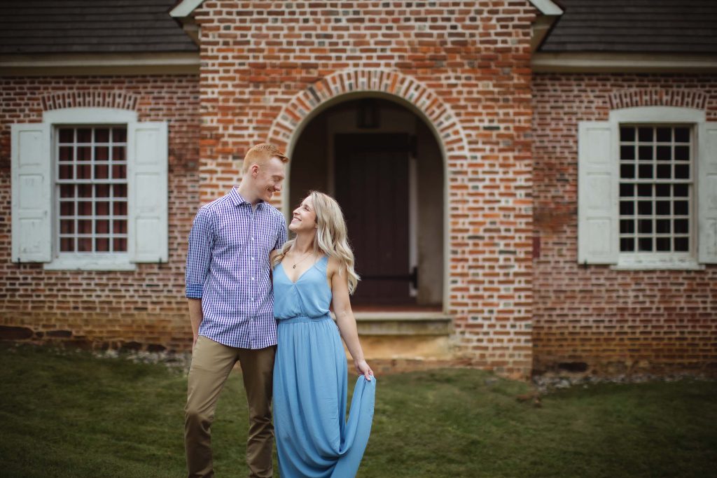 An engaged couple having their portrait taken in front of a brick house in downtown Annapolis.