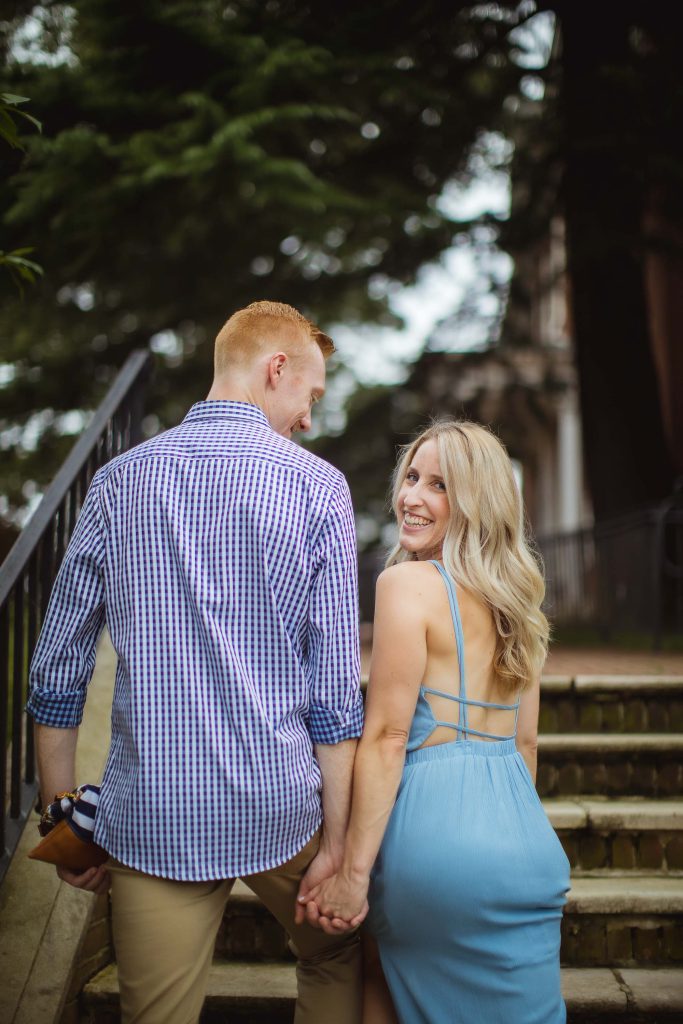 An engagement portrait of a couple holding hands on the steps of a downtown Annapolis building.