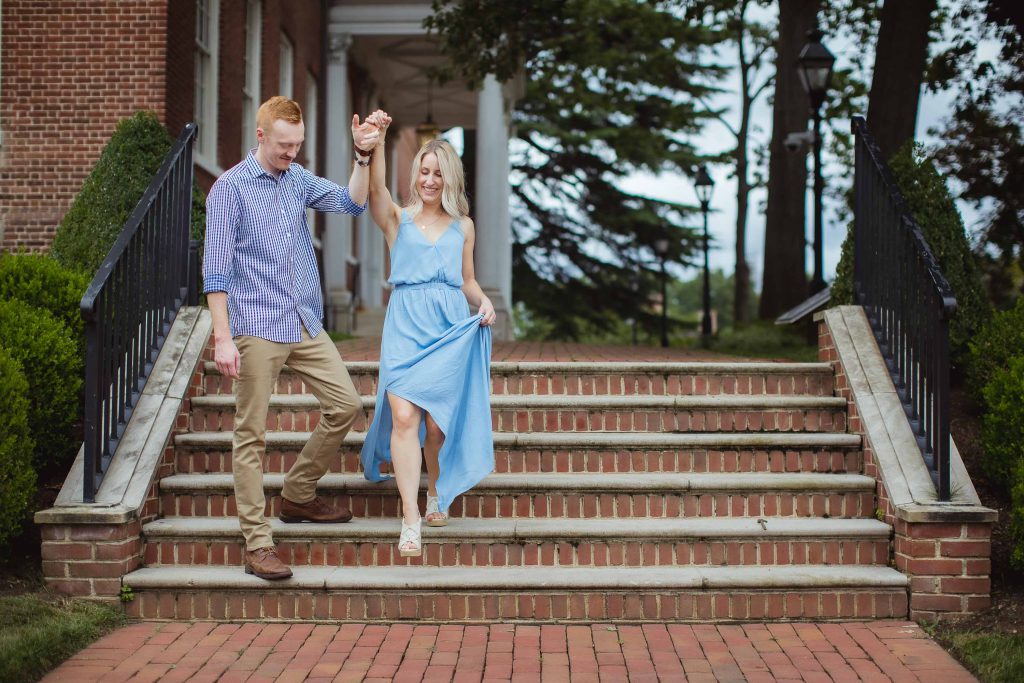 An engaged couple walking down the steps of a brick building in Downtown Annapolis, capturing a beautiful Engagement Photo.