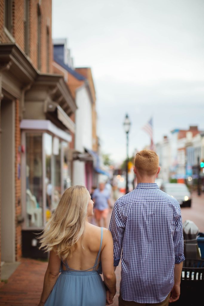 A couple walking down a downtown city street holding hands.