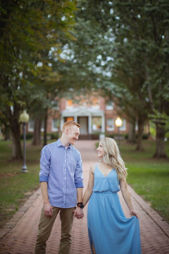 An engaged couple having an Engagement Session in Downtown Annapolis, holding hands on a brick walkway for their Portrait.