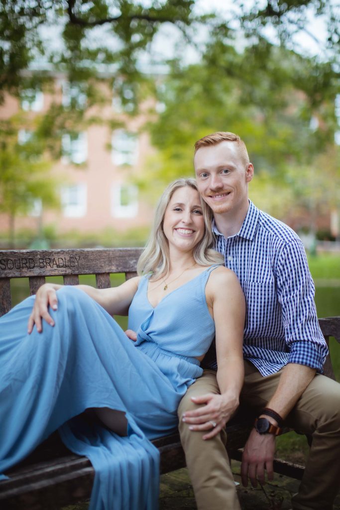An engaged couple posing for a portrait on a bench in Downtown Annapolis park.