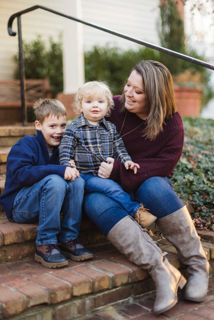 A family sits on the steps of their home, capturing beautiful portraits during their engagement session at Quiet Waters Park.