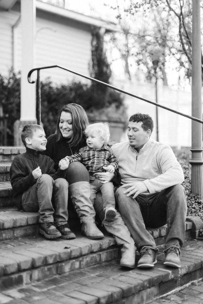An Engagement Session black and white photo of a Family sitting on steps at Quiet Waters Park.