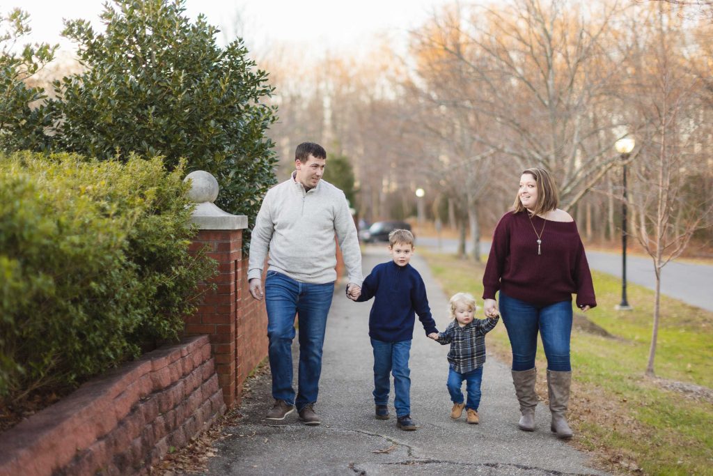 A family enjoys an Engagement Session walking down a sidewalk with their children, capturing beautiful Portraits.