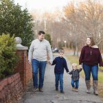 A family enjoys an Engagement Session walking down a sidewalk with their children, capturing beautiful Portraits.