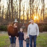 A family is standing on a brick walkway during their engagement session at Quiet Waters Park at sunset.